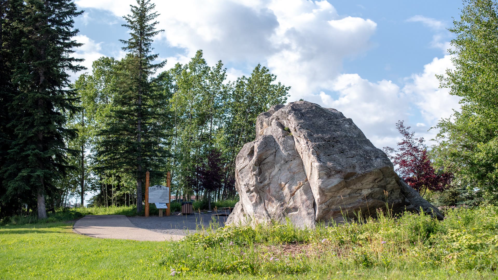 Large rock beside a paved trail in Rocky Mountain House